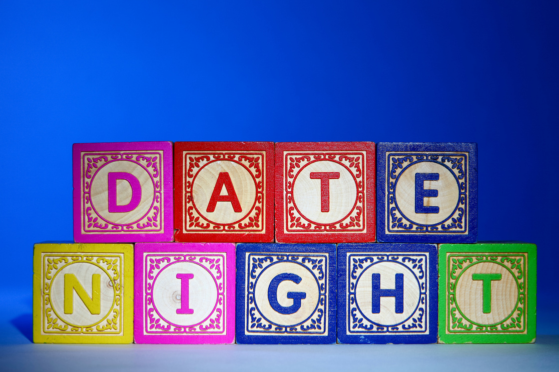 Wooden letter blocks on a blue background spelling out the words date night